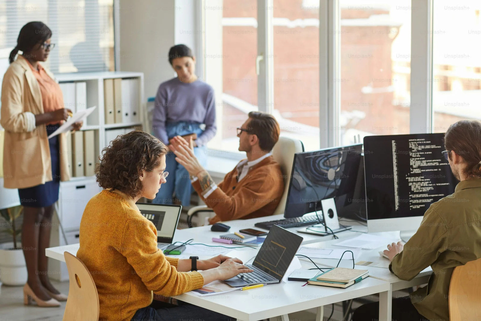 A team discussing software work around a shared desk